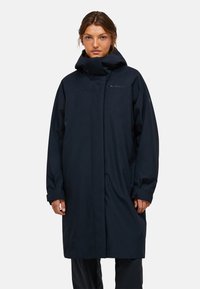 Cappotto lungo blu scuro con colletto alto, chiusura con zip e maniche larghe. Realizzato in materiale impermeabile, presenta un design minimalista.