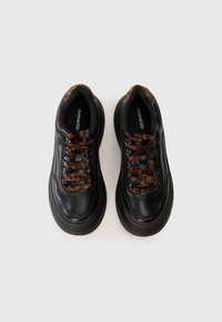 Black leather sneakers with a chunky sole, featuring leopard print laces and a smooth texture. Interior shows branded insole design.