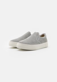 Grå ante-sneakers med elastiska sidopaneler, en tjock vit gummisula och en slät yta. Enkelt, minimalistiskt design utan mönster.