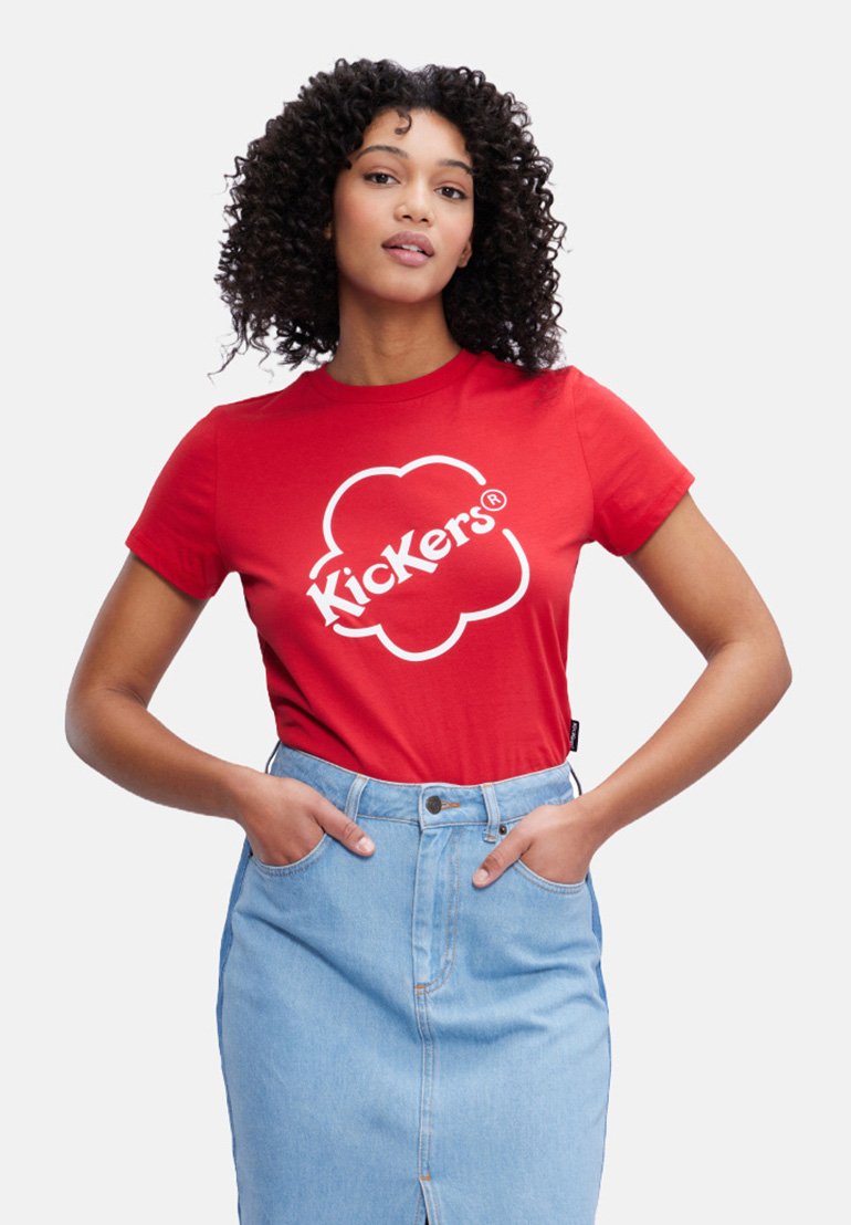 Camiseta de algodón roja con un logo blanco de 'Kickers' sobre un fondo en forma de nube, combinada con una falda de mezclilla azul clara.