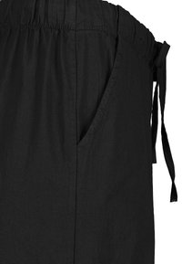 Schwarze Jogginghose aus leichtem Stoff, mit elastischem Bund, seitlichen Taschen und einer glatten, strukturierten Oberfläche.