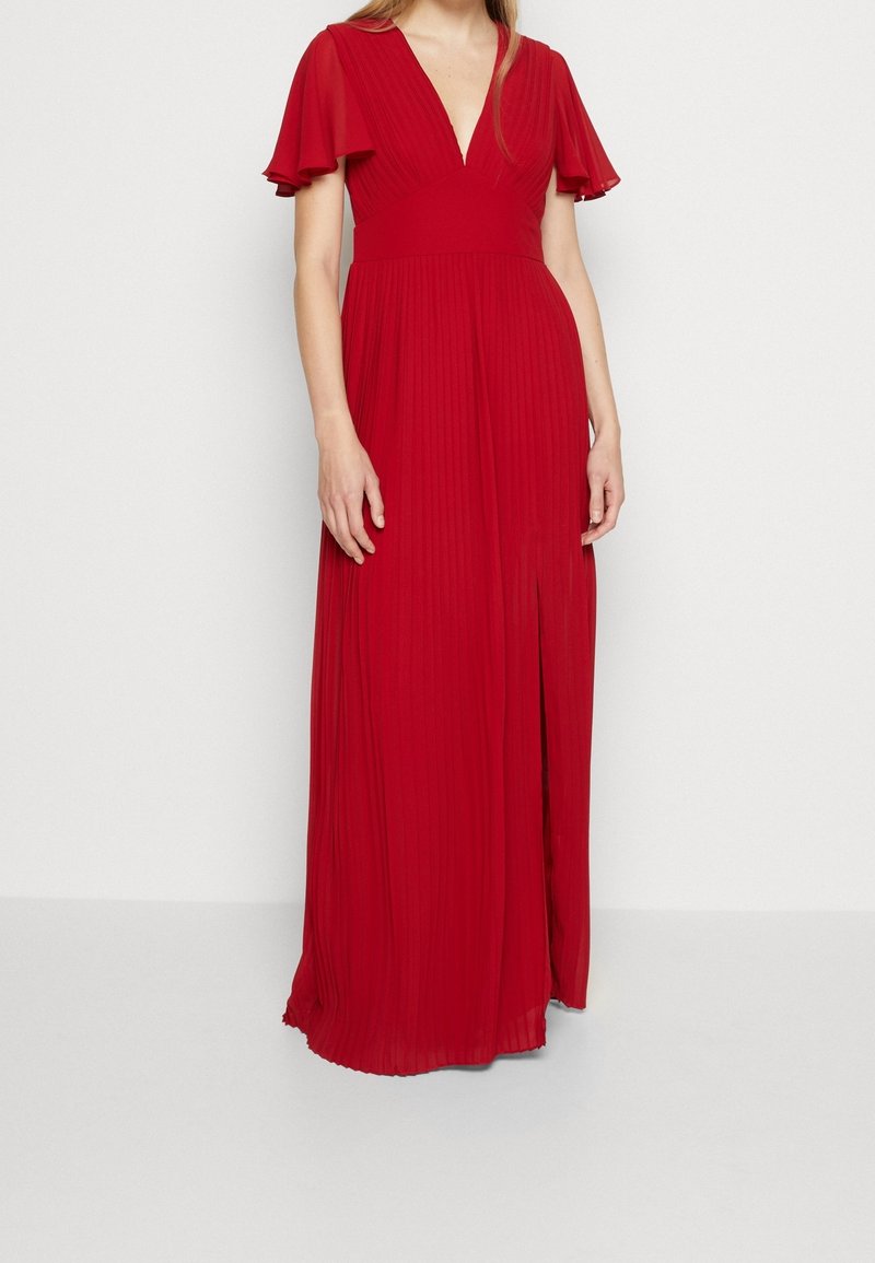 Robe maxi rouge avec un design plissé, un décolleté en V profond et des manches courtes volantées. Comprend une fente sur le côté pour plus de liberté de mouvement. Texture lisse.