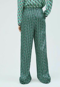 Zelené a námořnické pruhované kalhoty s širokým střihem, zdobené květinovým vzorem, elastickým pasem a hladkým textilním povrchem.