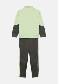 Chándal con parte superior verde menta y acentos gris oscuro, y pantalones gris oscuro a juego, ambos con finas franjas verdes a los lados. Textura de tela suave.