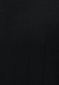 Κοντινό πλάνο μαύρου υφάσματος με υφή, λεπτό υφαντό μοτίβο και διακριτικές κάθετες γραμμές.