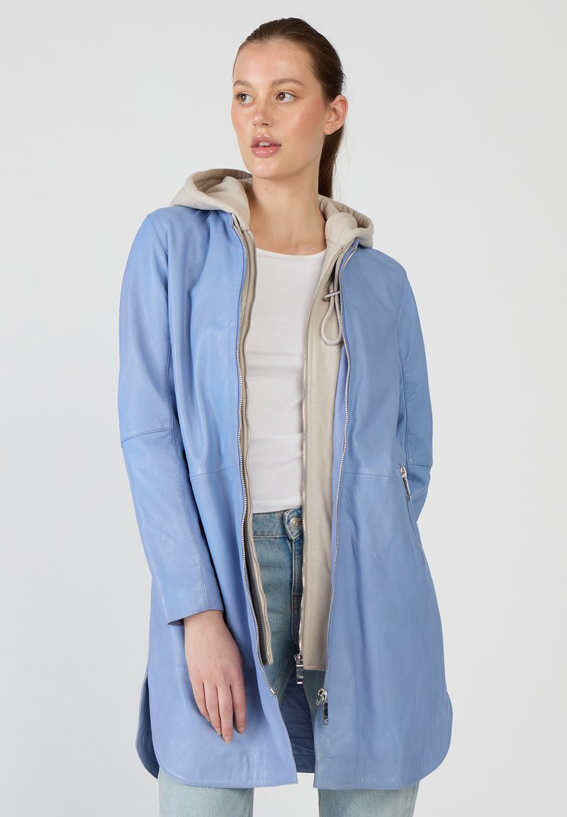 Vaaleansininen nahkatakki, jossa on vaaleanbeige huppu, täysipitkä vetoketju, kaksi sivutaskua ja hiukan pidempi takahelma.