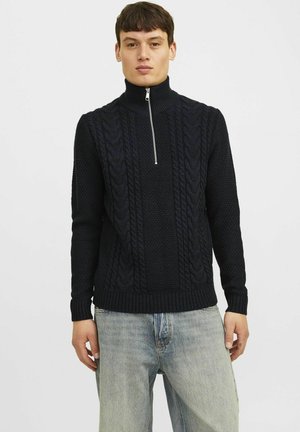 Suéter de punto azul marino con cuello alto y media cremallera, que presenta un patrón de trenzas texturizadas y puños y dobladillo acanalados.