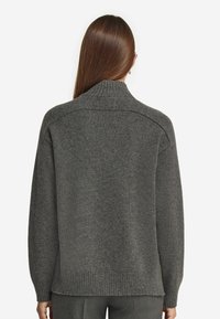 Grauer Wollpullover mit hohem Kragen, gerippten Bündchen und Saum. Hat eine strukturierte Oberfläche und einen lockeren Schnitt. Die Rückansicht zeigt die Schulternaht.