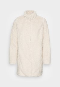 Abrigo de piel sintética color crema, suave y mullido, con un cuello alto y mangas largas. Presenta una abertura frontal sin cierres visibles y un ajuste holgado.