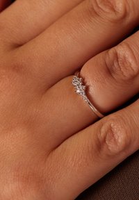 Bague en argent ornée de plusieurs petits diamants disposés en motif courbé, dotée d'un bandeau lisse et d'une finition polie.