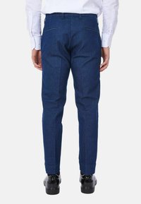 Pantaloni blu navy con vestibilità su misura, due tasche posteriori e una texture liscia. Abbinati a scarpe nere.