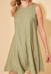 Ärmelloses A-Linien-Kleid aus hellgrünem Stoff mit strukturierter Oberfläche, mit Rundhalsausschnitt und knielangem Saum für eine lässige Passform.