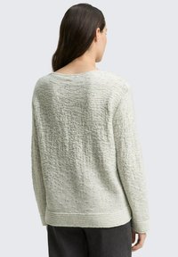 Pull vert clair en tricot texturé avec une coupe décontractée et un large col bateau, présentant un ourlet et des poignets côtelés. Vue de dos affichée.
