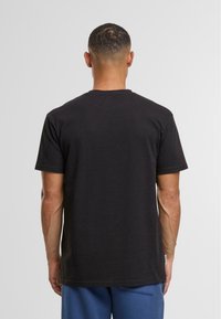 Schwarzes Baumwoll-T-Shirt mit Rundhalsausschnitt und kurzen Ärmeln, ohne sichtbare Muster oder Verzierungen auf der Rückseite.