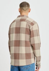 Brown and cream plaid shirt made of woven fabric with a textured finish, featuring a button closure and standard collar.