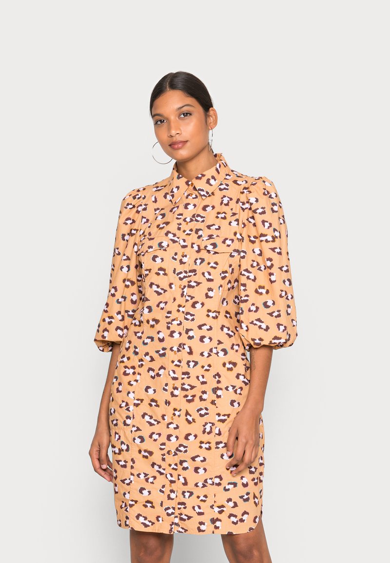 Vestido com padrão de oncinha em tecido laranja claro, apresentando um design de botões, mangas curtas e bufantes, e dois bolsos frontais.