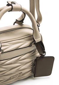 Borsa a mano in pelle beige con design trapuntato, caratterizzata da manici arrotondati, una tracolla removibile e un piccolo tag marrone.