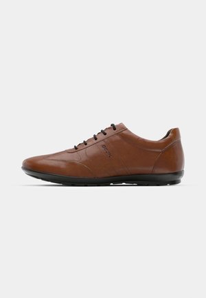 Brown leather shoes with a sleek, low-profile design, featuring black laces and subtle stitching details on the side. Black rubber sole.