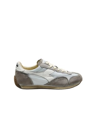 Sneaker in suede bianco e grigio a profilo basso con lacci bianchi e suola in gomma, vista laterale su sfondo bianco.
