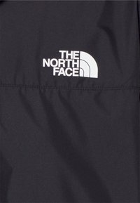 Tissu noir avec logo blanc "The North Face" et motif en demi-cercle imprimé.