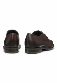 Scarpe in pelle marrone con punta arrotondata, design minimalista con lacci, superficie liscia e tacco impilato per una maggiore stabilità.