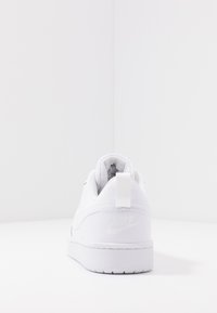 Vit sneakers med en slät läderöverdela, vadderad foder, bakre dragflik och låg profil. Har en diskret präglad logotyp på hälen.