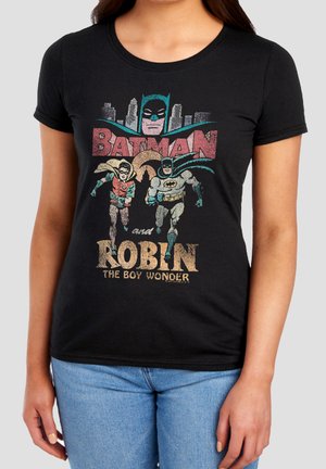 Woman wearing black shirt with colorful vintage Batman and Robin running graphic and text "Batman and Robin The Boy Wonder."