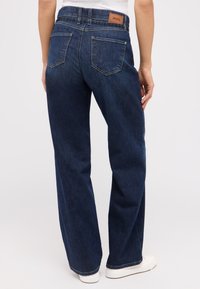 Dunkelblaue Jeans mit geradem Bein, fünf Taschen und einem Lederlogo-Patch am hinteren Bund. Texturierter Stoff. 