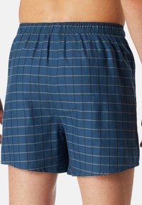 Blue checkered boxers with a soft fabric, featuring a flexible waistband and subtle grey lines forming a grid pattern.