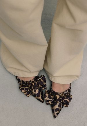 Puntige ballerina's in een luipaardprint met een grote strikaccent. Het materiaal lijkt glanzend en is in goud- en donkerbruintinten.