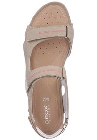 Sandal in pelle beige con cinturini regolabili, soletta morbida, design perforato e cuciture rosa. Presenta dettagli in metallo.