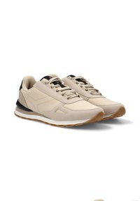 Zapatillas beige con parte superior de ante texturizado, acentos en negro, diseño de cordones y suela de goma con un patrón de tracción marrón.