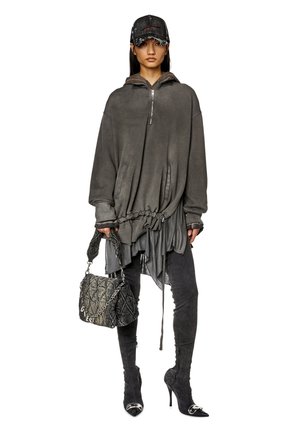 Oversized grå sweatshirt med lynlås og snøredetalje, parret med teksturerede sorte leggings og spidse stilethæle, mens der holdes en mønstret håndtaske.