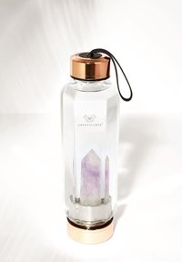 Bouteille d'eau en verre transparent de forme hexagonale, dotée d'un couvercle en métal rose doré et d'un cristal violet à l'intérieur. Poignée texturée et sangle attachante incluses.