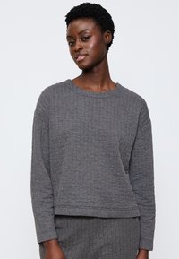 Grau gestreiftes Langarmoberteil mit rundem Ausschnitt. Weicher, strukturierten Stoff, cropped Design und lockere Passform.