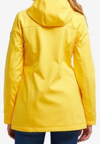 Yellow softshell jacket with a fitted design, hood, and seam detailing. Smooth texture with no visible hardware or patterns.