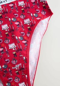 Red fabric underwear featuring a repeated pattern of cakes, candelabras, hearts, and decorative accents, with a smooth inner lining.