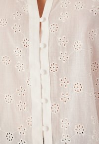 Witte linnen blouse met bloemenborduurwerk, uitsnijdingen, knoopsluitingen en een lichtgewicht, gestructureerde stof.