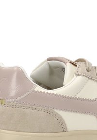 Zapatilla con una combinación de cuero beige liso y de ante, acentos en rosa pálido y una suela de goma texturizada. Presenta cordones y detalles de costura.
