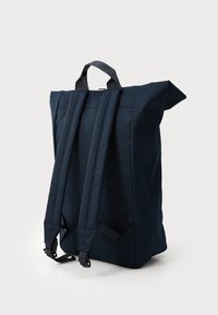Granatowy plecak z materiału, z regulowanymi ramiączkami, uchwytem na górze, prostokątnym kształtem i eleganckim designem. Posiada minimalną ilość okuć i brak widocznych wzorów.