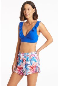 Niebieski stanik bikini z falbankami o głębokim dekolcie w kształcie litery V, zestawiony z kwiatowymi szortami kąpielowymi w różowe, niebieskie i białe wzory, z elastycznym paskiem w talii.