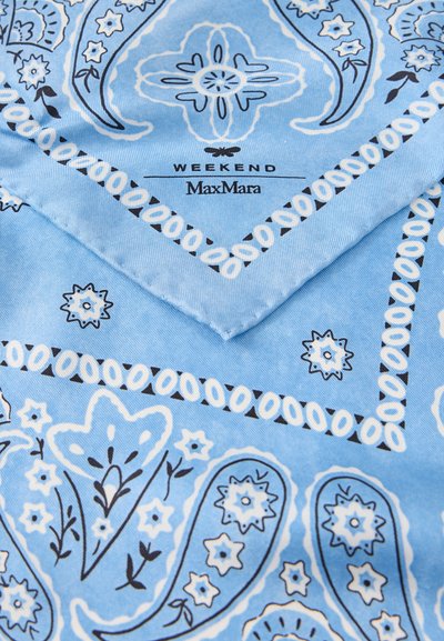 Ανοιχτό μπλε ύφασμα με λευκά και μαύρα σχέδια παϊνσλεϊ και λουλουδιών, διπλωμένη γωνία που δείχνει το κείμενο "WEEKEND MaxMara".