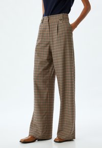 Wijde pantalons in een ruitpatroon met bruine, oranje en zwarte tinten. Hoge taille met plooien en een gladde stoftextuur.