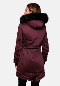 Bordeaux gewatteerde jas met een afneembare zwarte faux-fur capuchon, voorzien van een verstelbare taillekoord en een iets langere achterkant.