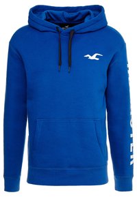 Blue pullover hoodie made of soft fabric, featuring a front pouch pocket, black drawstrings, and white logo detail on the left sleeve.