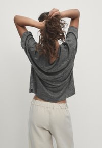 Szara, przycięta koszulka o luźnym kroju, z luźnym tyłem i krótkimi rękawami, zestawiona z kremowymi spodniami z elastycznym pasem. Prosty design, miękka faktura.