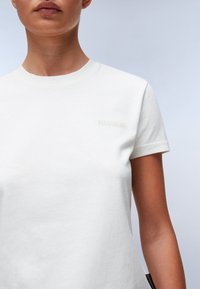 Witte katoenen T-shirt met korte mouwen. Beschikt over een kleine, tonale logo borduring op de borst. Zachte textuur en klassieke ronde hals.