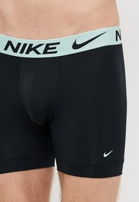 Mustad venivad bokserpüksid, millel on mündiroheline elastne vöörihm, millel on kiri "NIKE" ja allosas ees väike must logo. Sile pind.