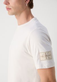 Calvin Klein Jeans BADGE REGULAR TEE - Pamata T-krekls - ivory