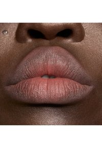 Gros plan sur des lèvres pleines dans une teinte rose douce, avec une texture lisse, des lignes subtiles et une finition brillante sur une peau foncée.